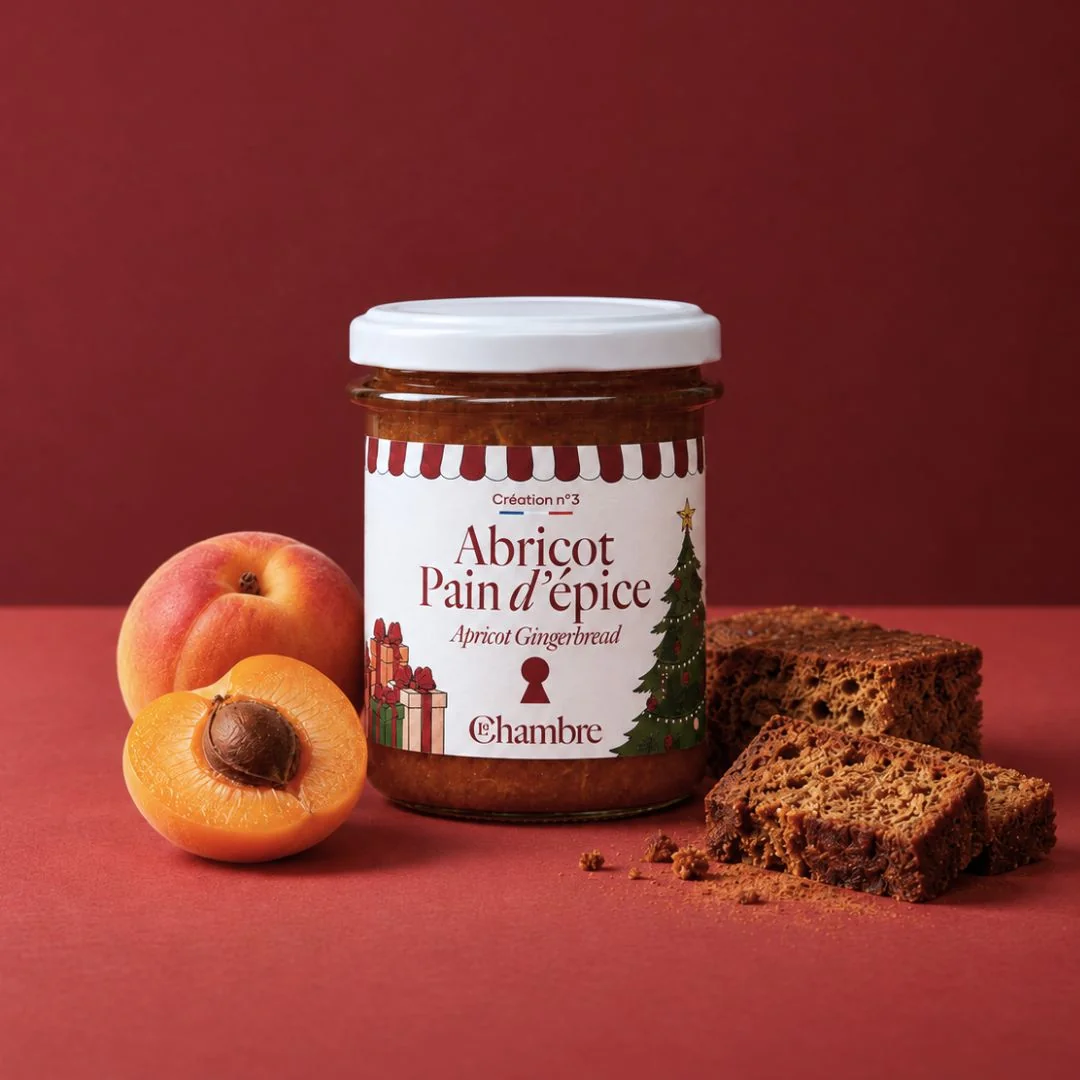 Pot de confiture Abricot Pain d'épice de La Chambre sur fond rouge, avec un abricot entier, un abricot coupé en deux et deux tranches de pain d'épices