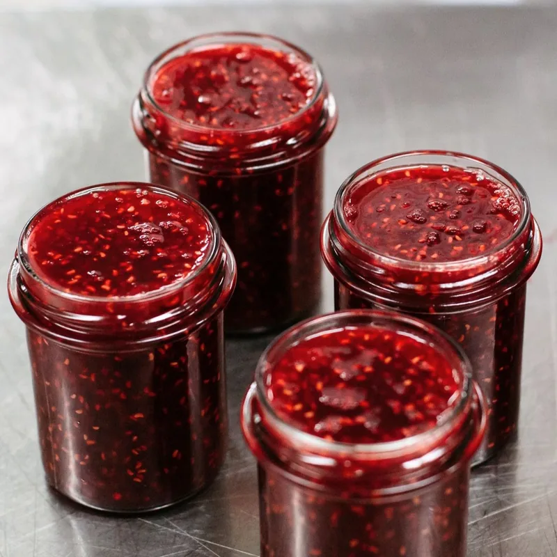 Pots de confiture de framboise ouverts dans l'atelier La Chambre