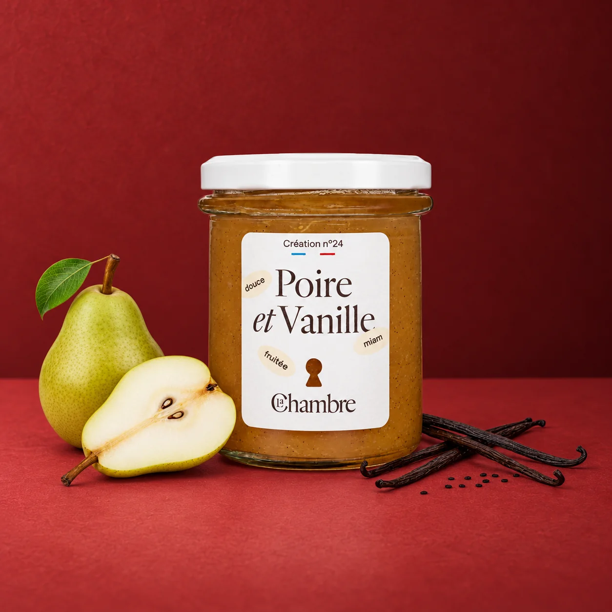 Pot de confiture Poire et Vanille de La Chambre sur fond rouge, avec une poire entière, une demi-poire et des gousses de vanille