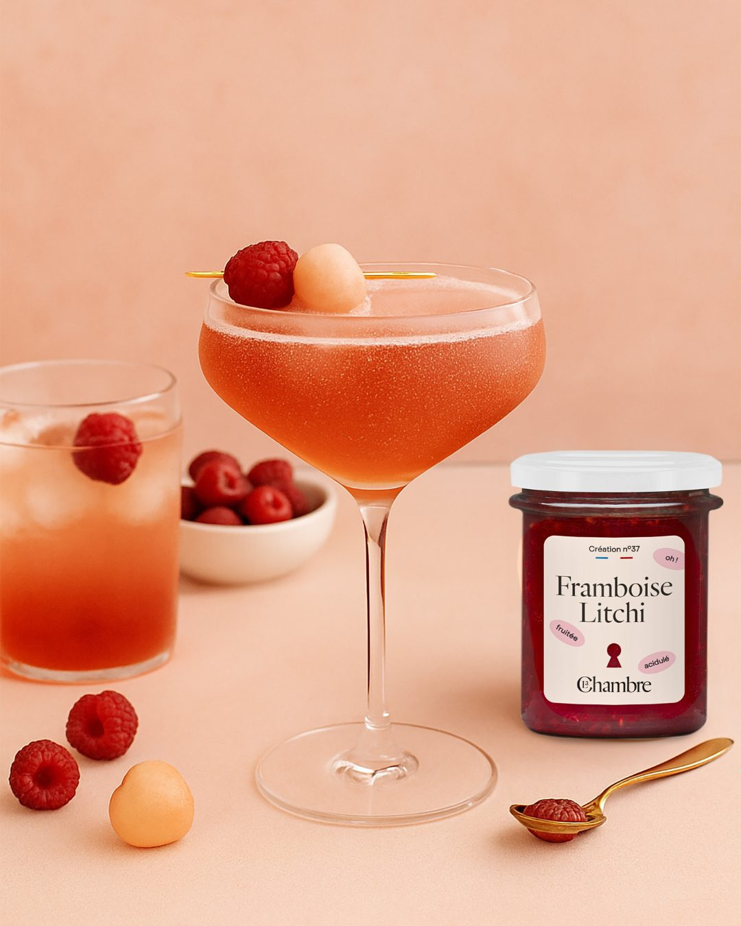 The 100g raspberry lychee jam jar next to a red-orange cocktail made with La Chambre products